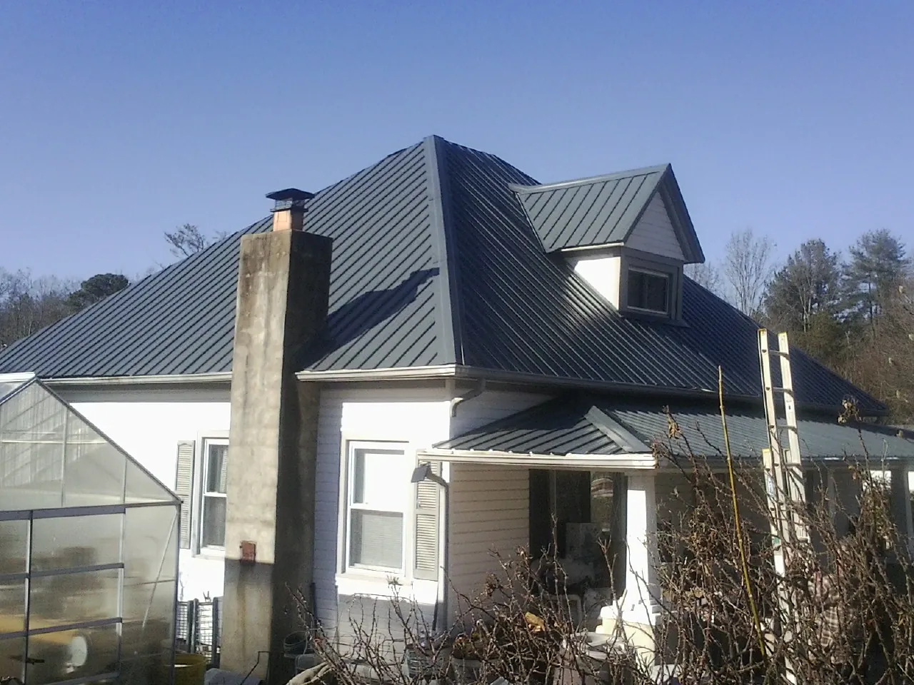 Dark blue standing seam metal roof on a white farmhouse with dormer — Slate & Tile Roof Repair by Roofing Brothers in Cook