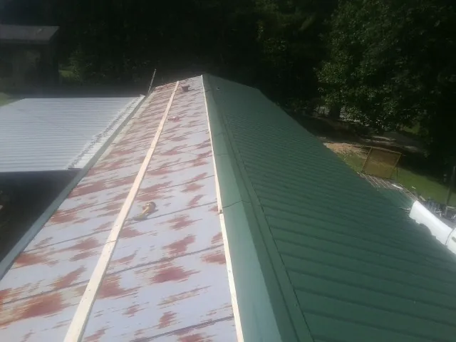 Old rusted panels beside newly installed green metal roofing — Wind Damage Roof Repair by Roofing Brothers in Cook