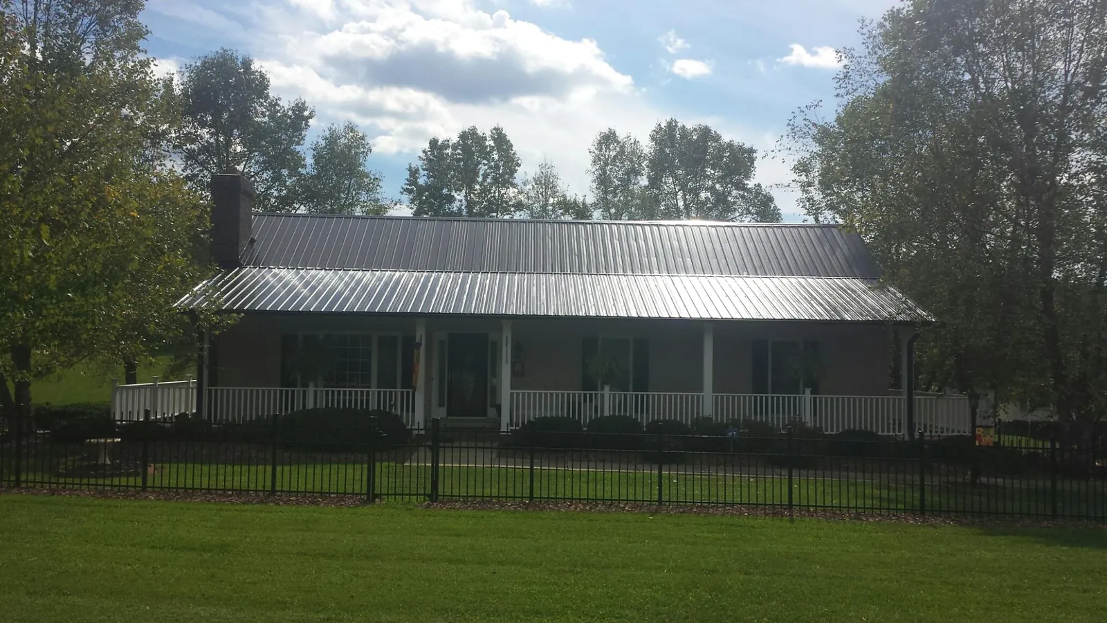 Gray metal roof on a brick ranch with a full width front porch — Gutter Guard Installation work by our crew in Cook