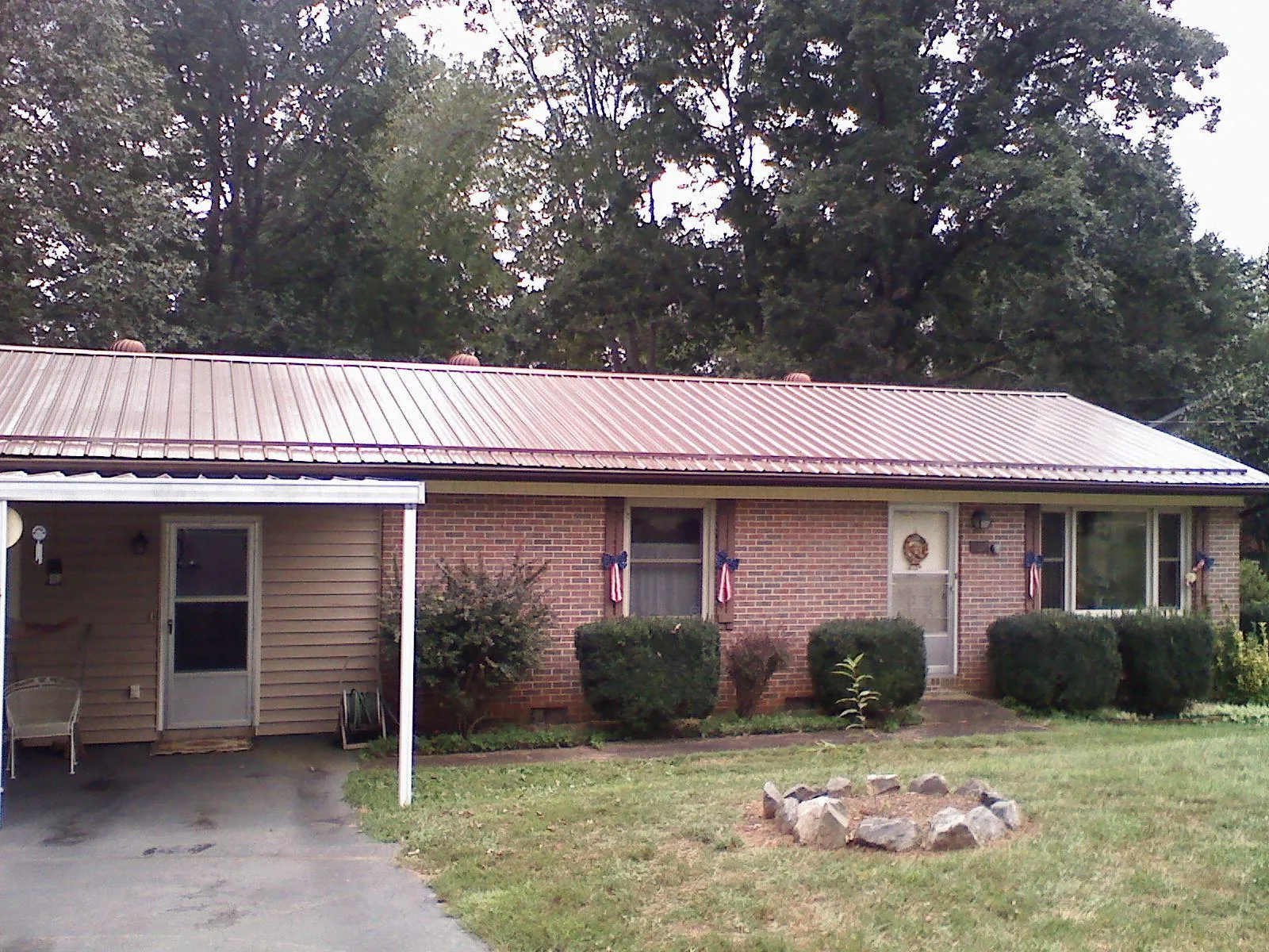 Bronze metal roof and carport on a brick ranch home — Roof Repair work by our crew in Cook
