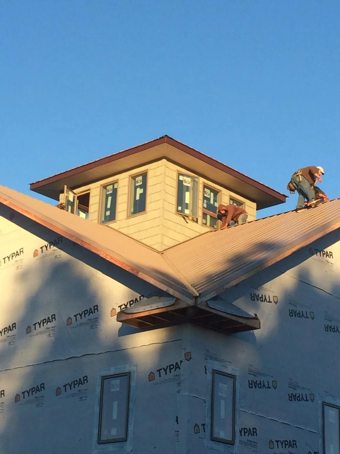 Roofers working around a rooftop cupola on a new metal roof at sunset — Roof Waterproofing in Cook by Roofing Brothers